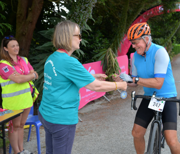 Coast and Clay Sportive Cornwall Hospice Care Employee handing a finisher their medal